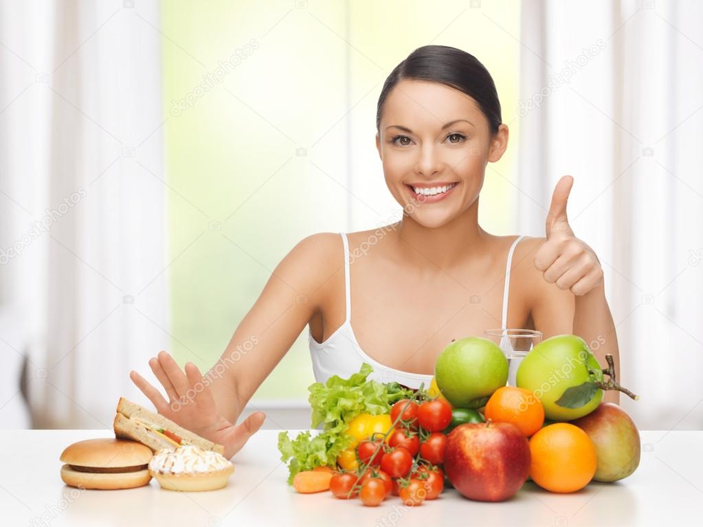 A woman with fruits rejecting hamburger and cake 